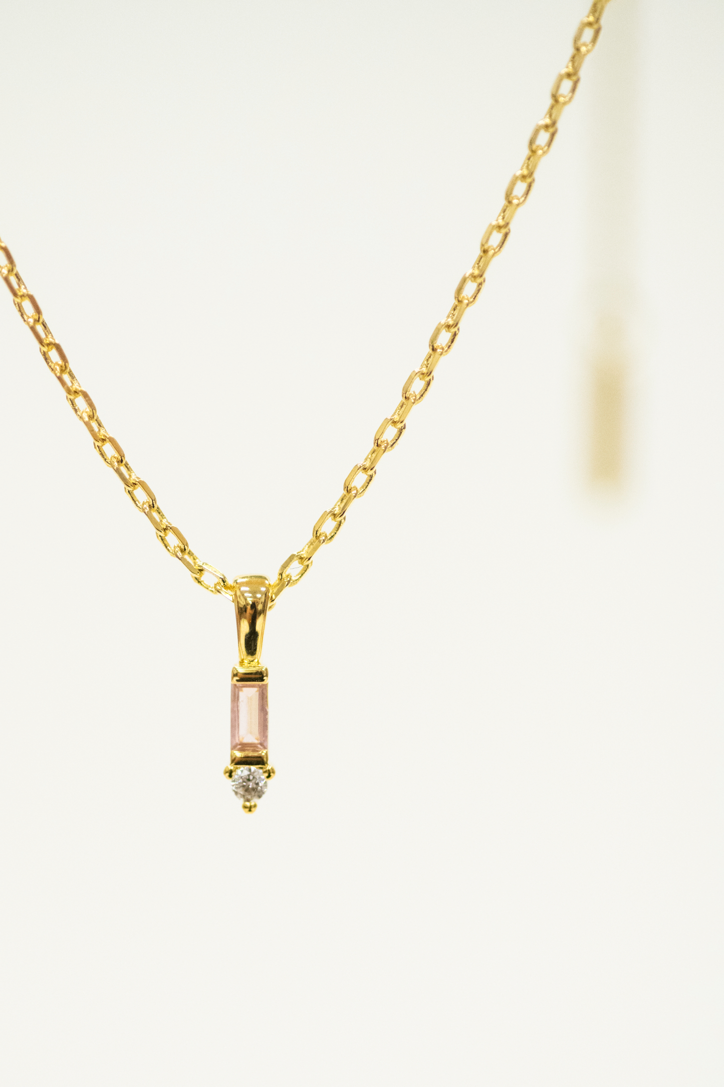 Gold necklace with a small pendant on a white background