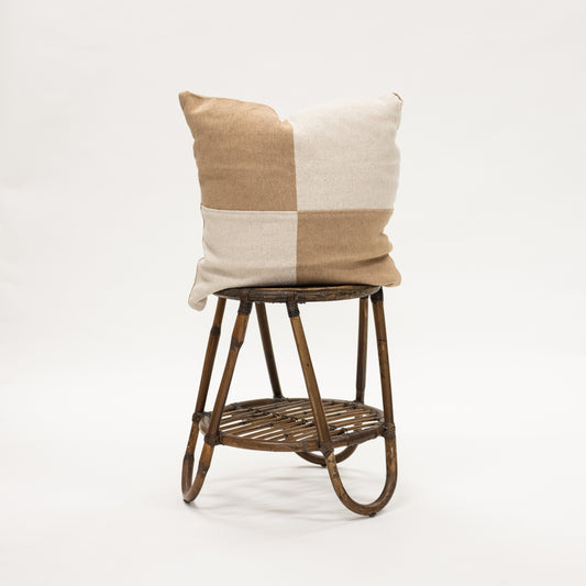 Cheque Throw Pillow 22" in Tan and Cream sitting on a wicker stool