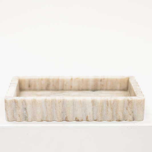 A beige marble tray with fluted sides.