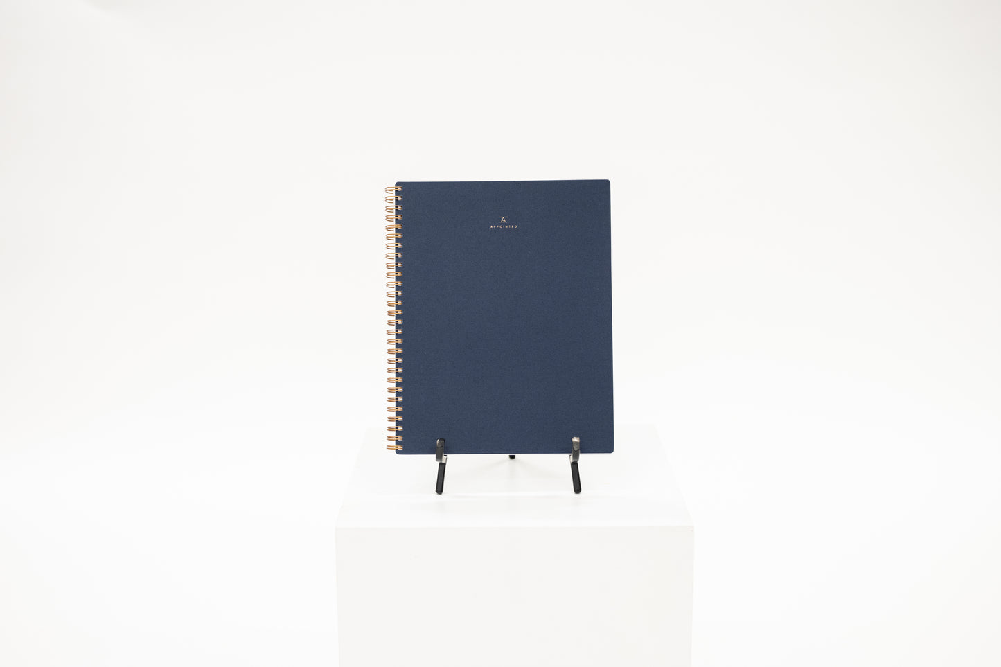 a navy linen covered workbook with brass coil binding