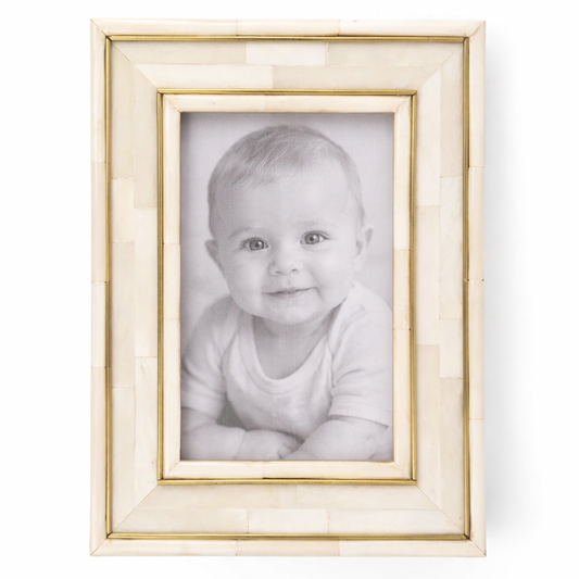 Framed photo of a baby with a gold and beige border on a white background