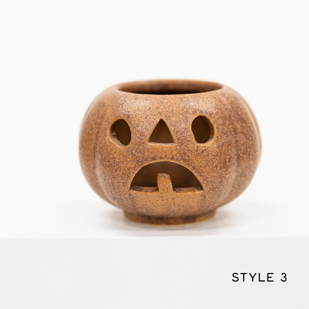 A small pumpkin-shaped ceramic candle holder with a carved sad face, in a speckled brown glaze, shown on a white background with the text 'STYLE 3' in the bottom right corner.