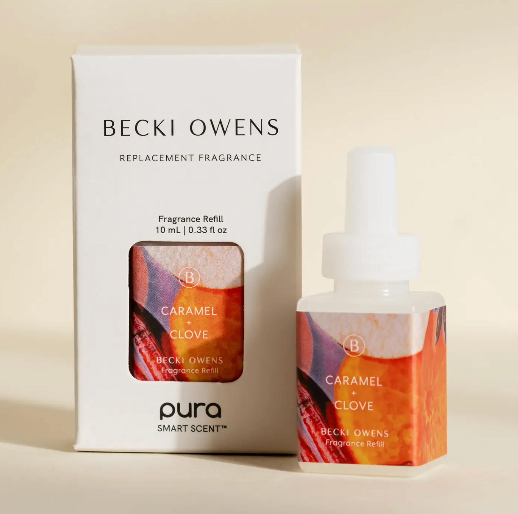 Becki Owens Pura Smart Scent Caramel + Clove fragrance refill shown with its white retail box and the refill bottle itself on a warm beige background.