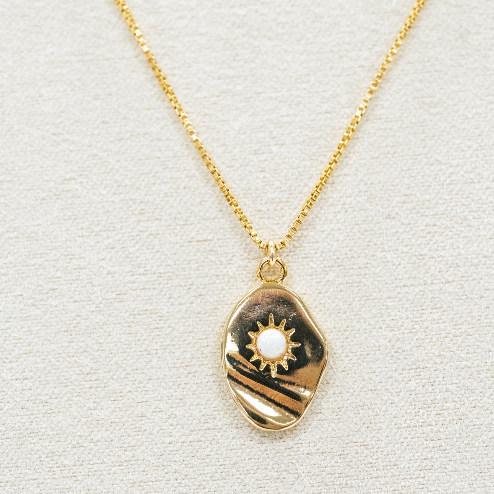 gold necklace featuring a pendant and small white opal. with a gold chain necklace
