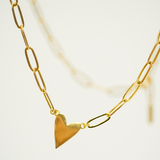 Gold heart-shaped pendant on a gold chain against a light background