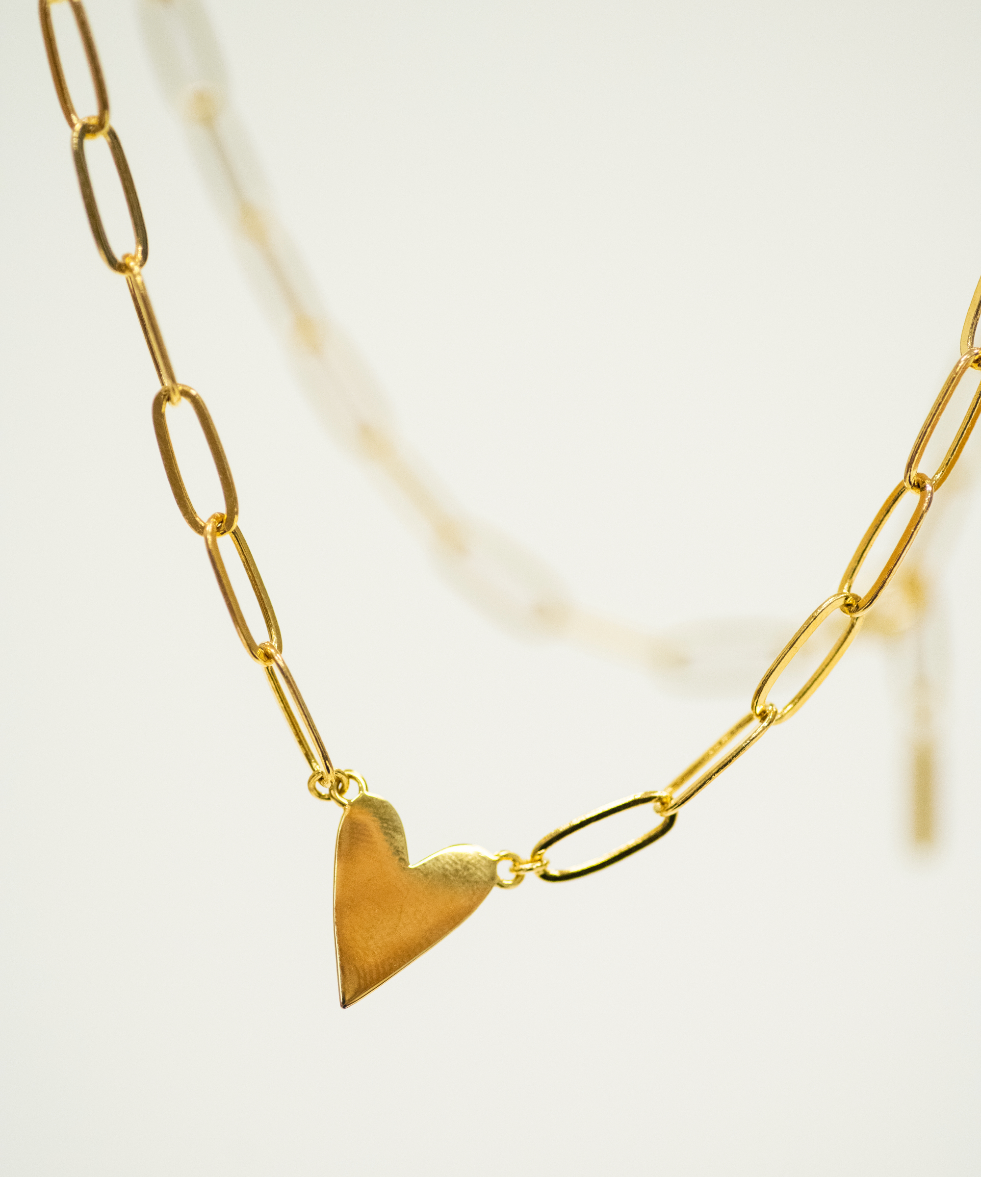Gold heart-shaped pendant on a gold chain against a light background