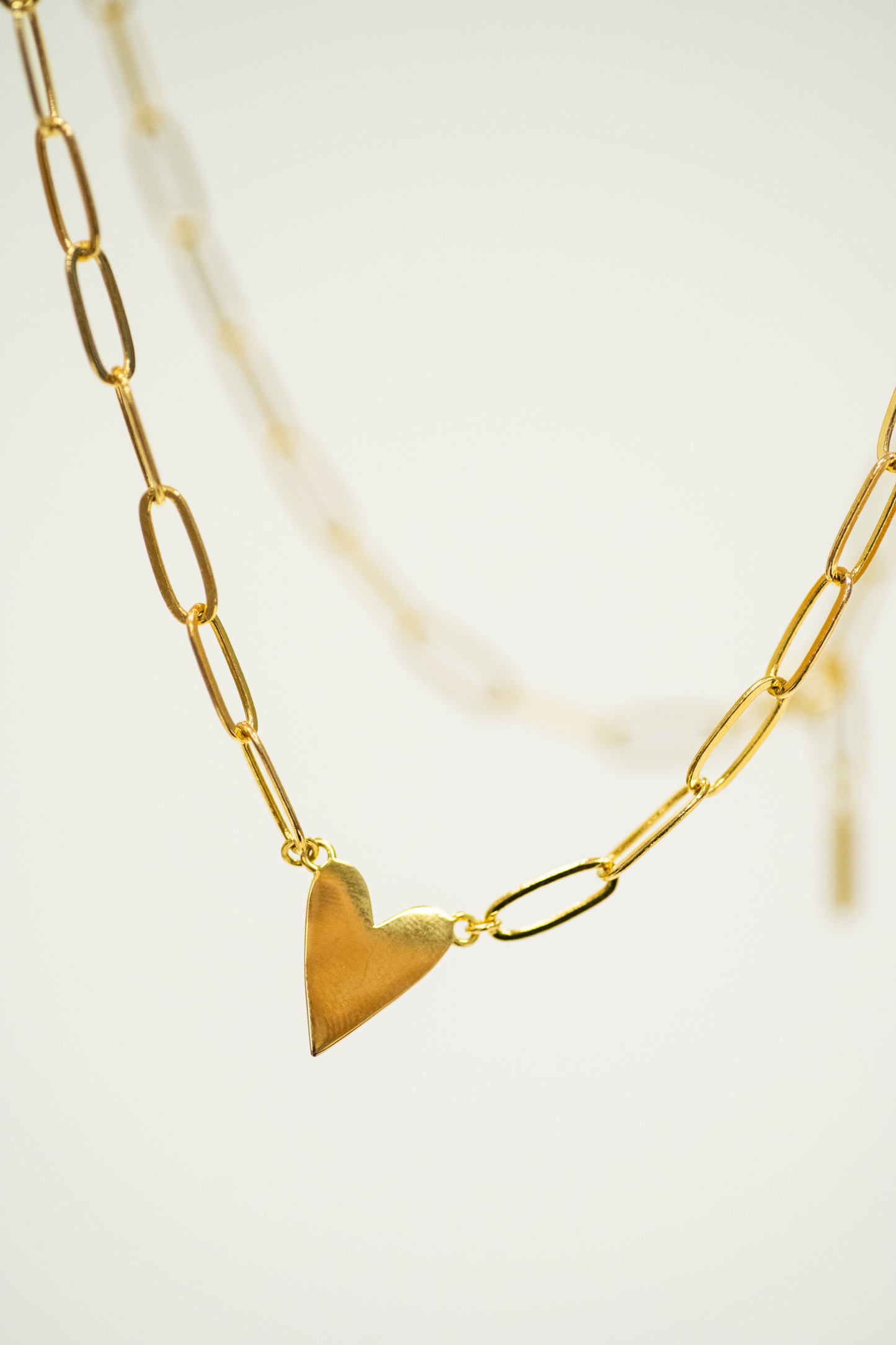 Gold heart-shaped pendant on a gold chain against a light background