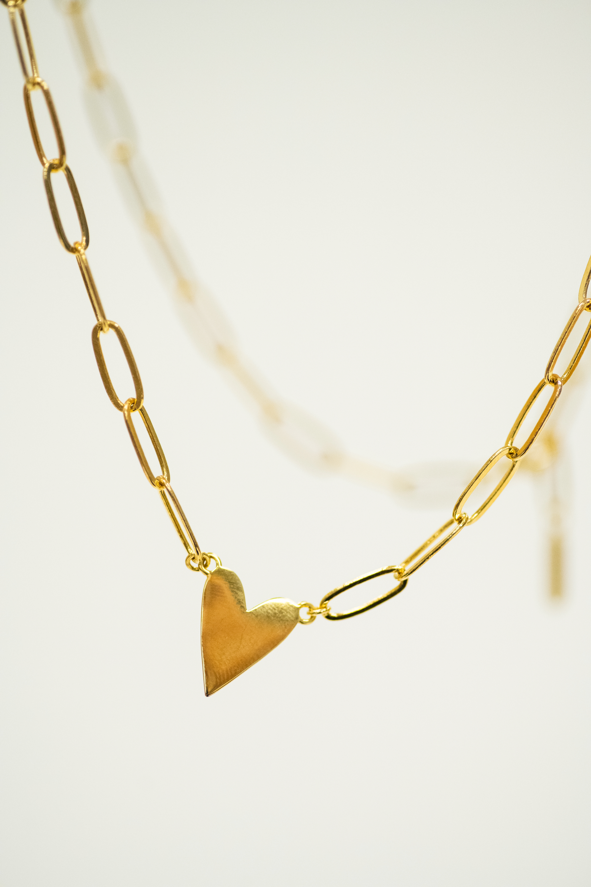 Gold heart-shaped pendant on a gold chain against a light background