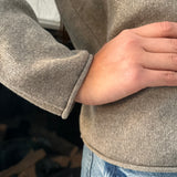 Close-up of a person wearing a gray sweater with a blurred background