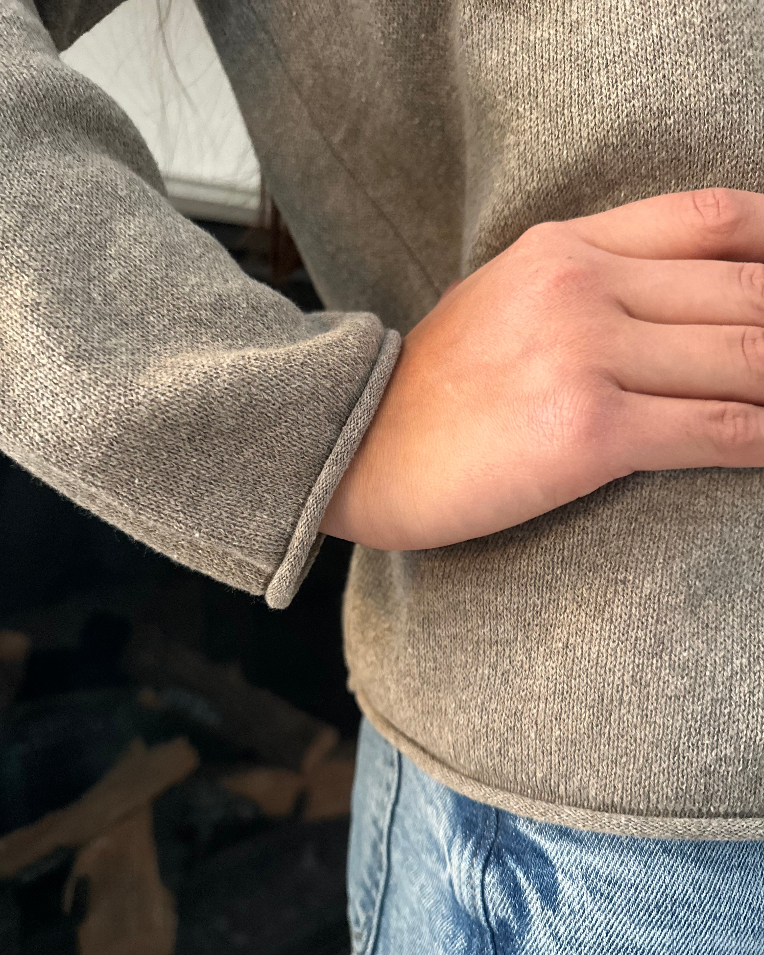 Close-up of a person wearing a gray sweater with a blurred background