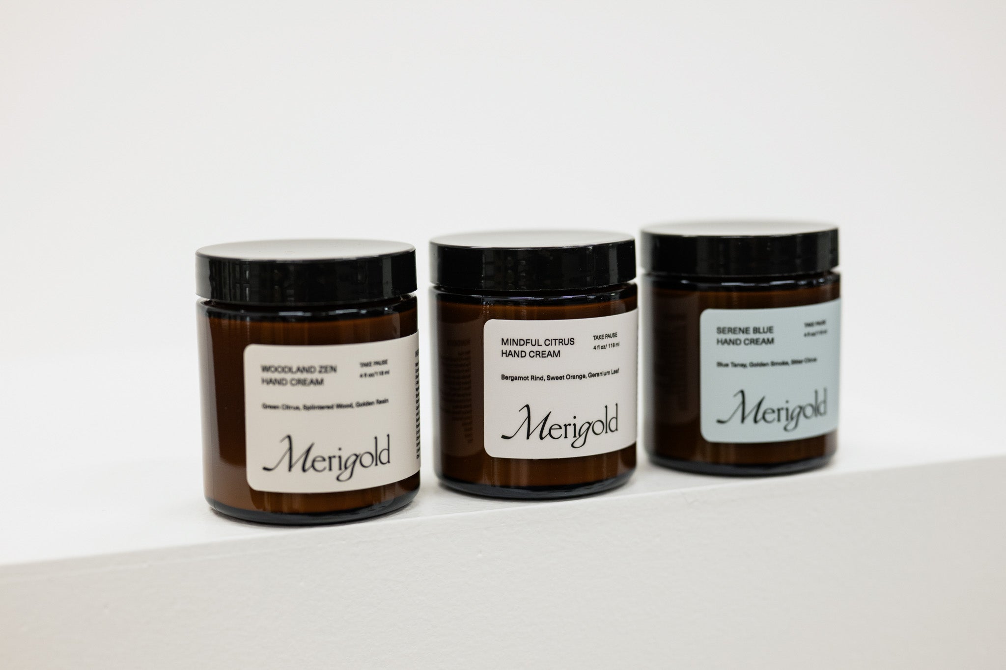 Three jars of Merigold hand cream on a white background