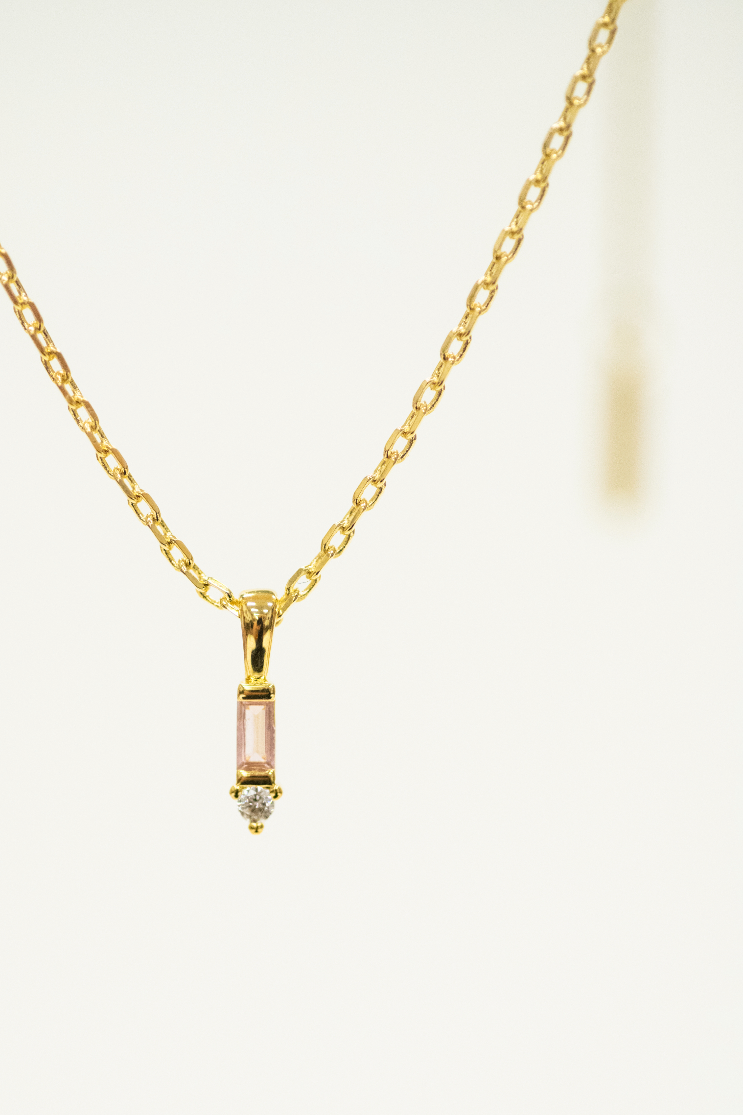 Gold necklace with a small pendant on a white background