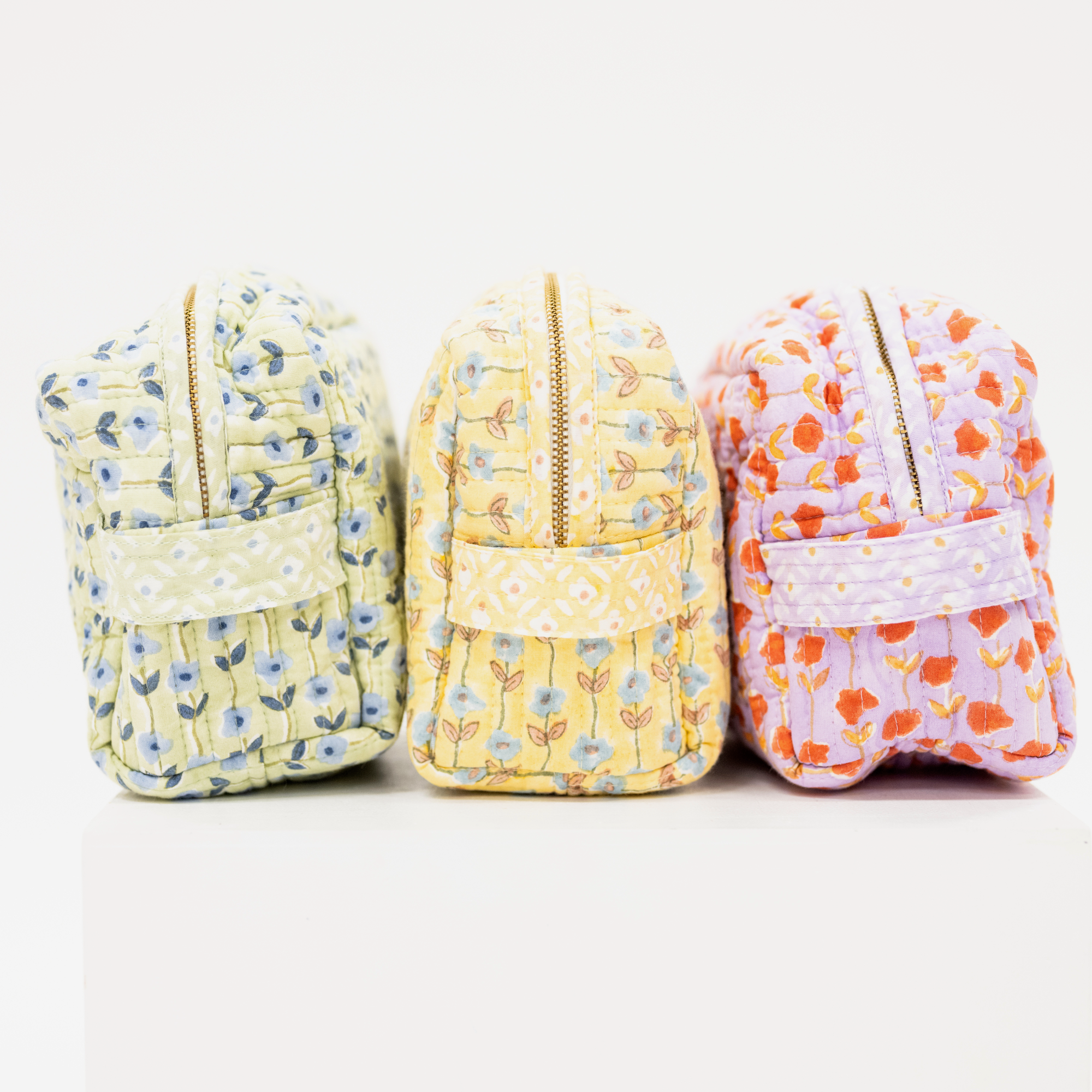 Three floral-patterned zip-up pouches on a white background