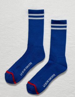 Pair of blue socks with white stripes and red accents on a light gray background