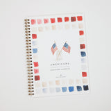 A spiral-bound watercolor workbook titled 'AMERICANA' with a white cover, decorated with a border of red, white, and blue watercolor paint swatches and two small American flags near the center. The brand 'Emily Lee Studio' is printed at the bottom.