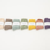 7 different colored cloud socks on a white surface, each with a label indicating the brand le bon shoppe