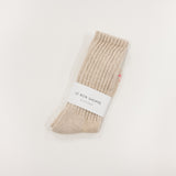 Beige ballet sock with a white label on a light gray background, le bon shoppe