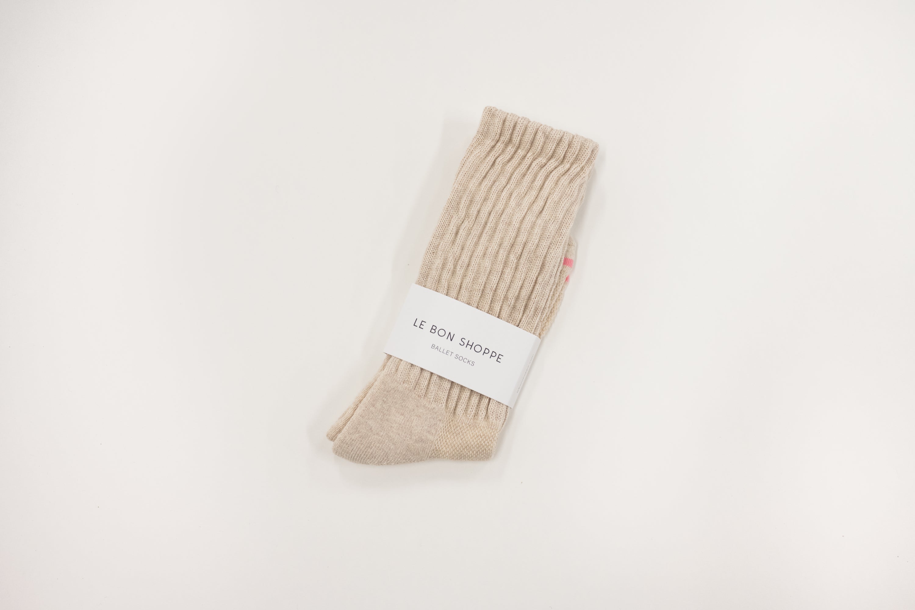 Beige ballet sock with a white label on a light gray background, le bon shoppe