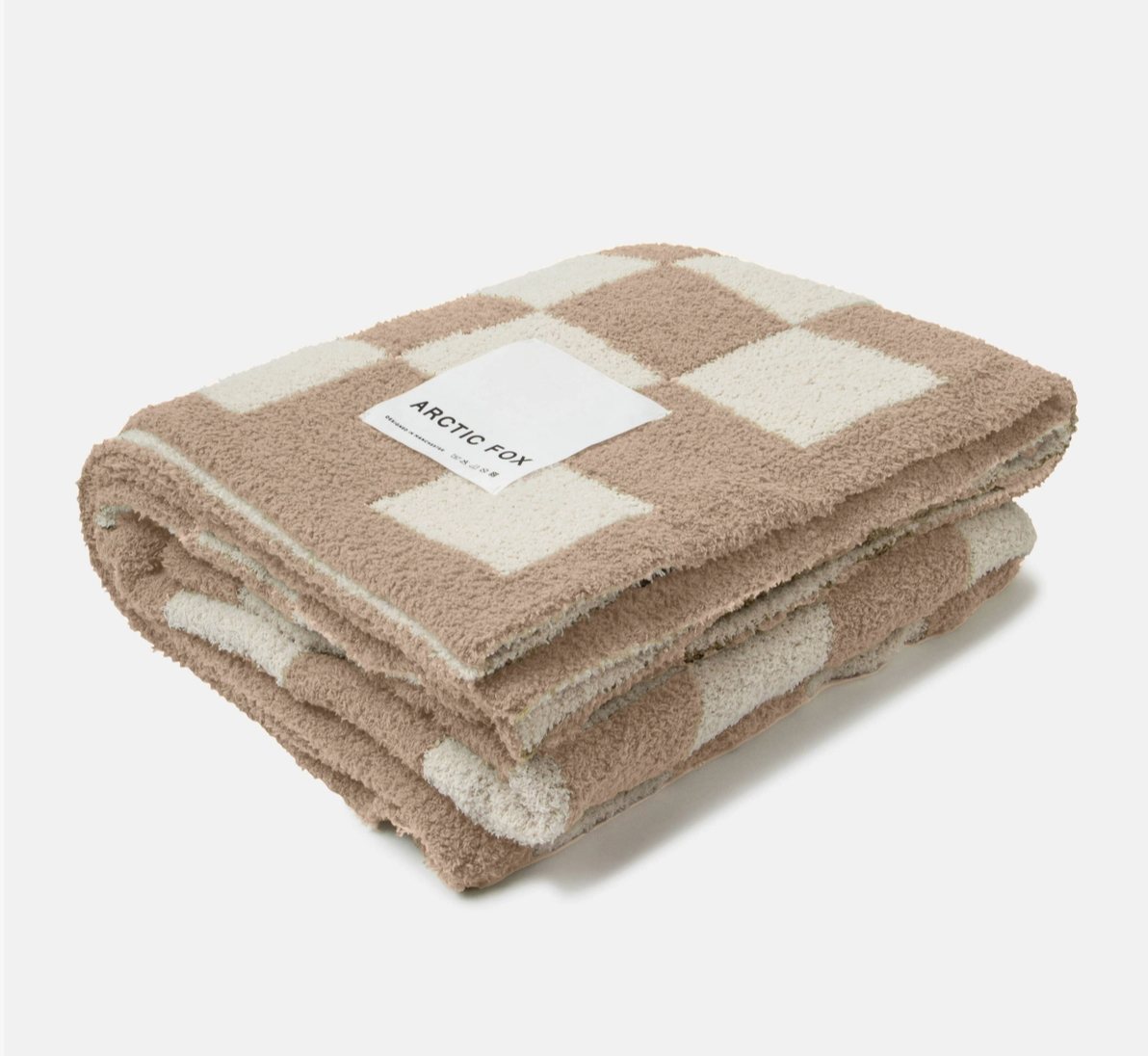 A folded fleece throw blanket with a beige and cream checkerboard pattern, featuring a white paper label that reads 'ARCTIC FOX'.