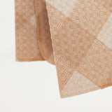 Folded fabric with a diamond pattern on a light background