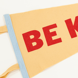 red screen print with words "be kind" on cream colored felt pennant