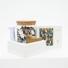 Jigsaw puzzle pieces in a container with a wooden lid on a white surface