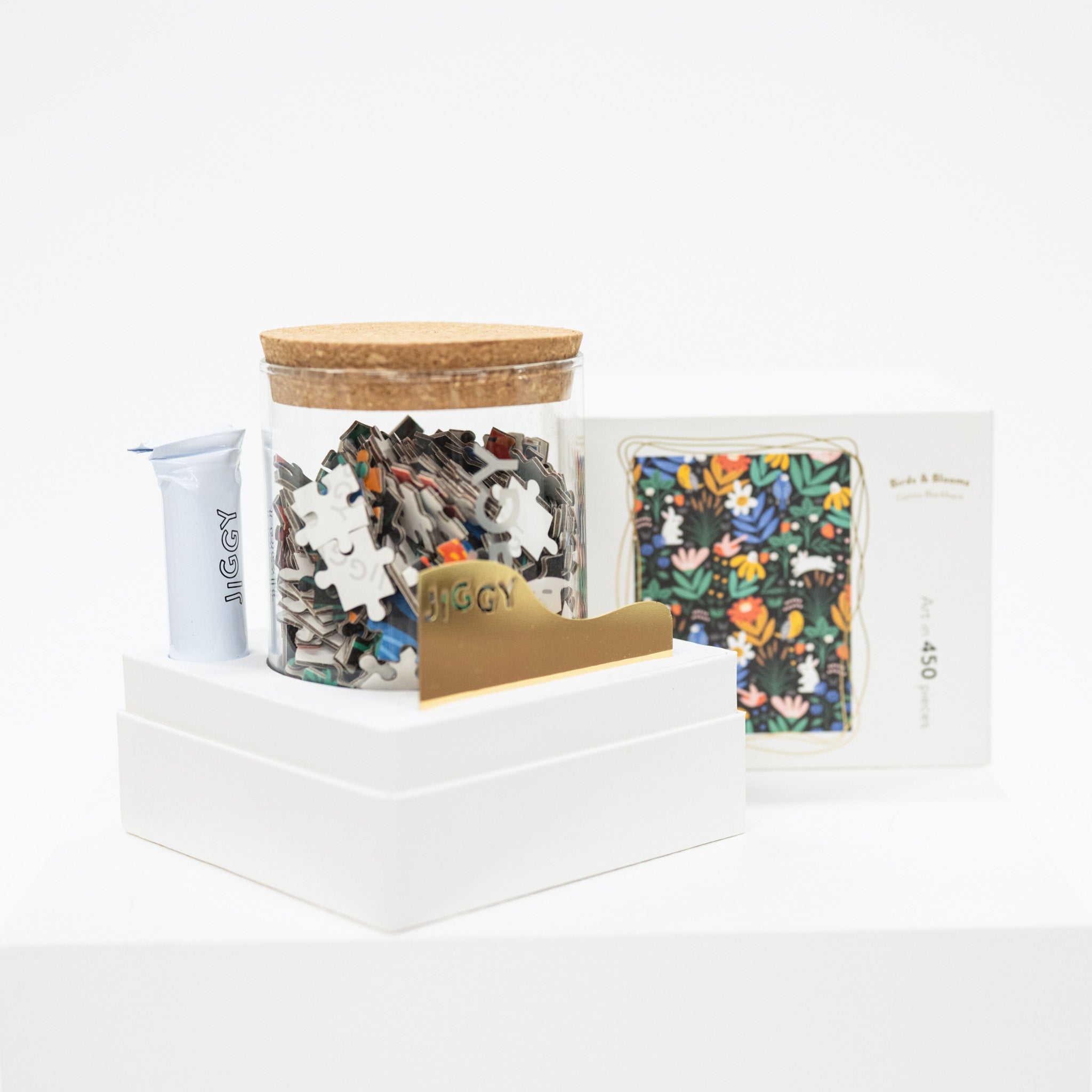 Jigsaw puzzle pieces in a container with a wooden lid on a white surface