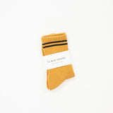 mustard yellow tall crew sock with a white label saying le bon shoppe