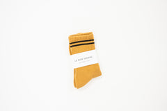 mustard yellow tall crew sock with a white label saying le bon shoppe