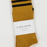 Mustard yellow socks with black stripes and a visible label on a white background