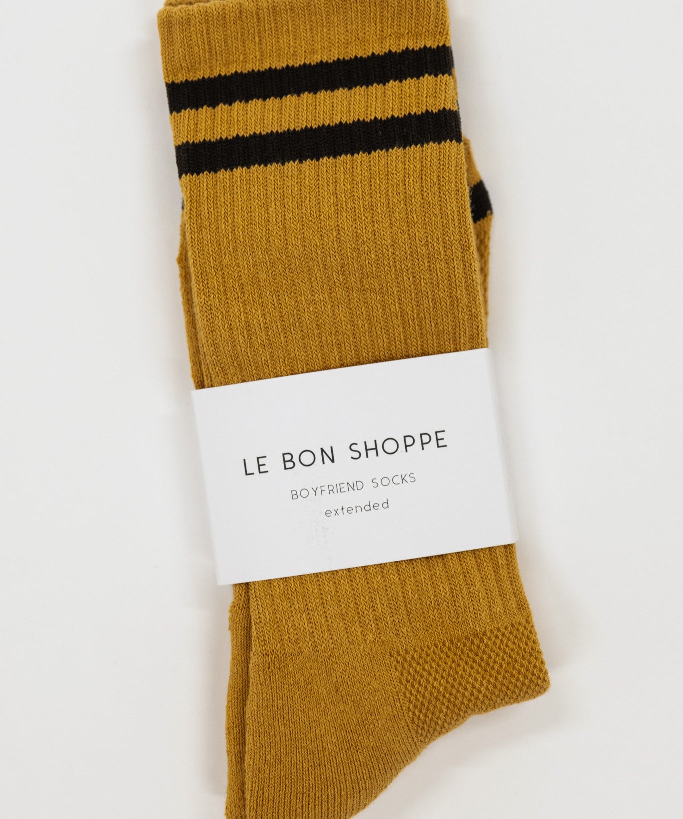 Mustard yellow socks with black stripes and a visible label on a white background