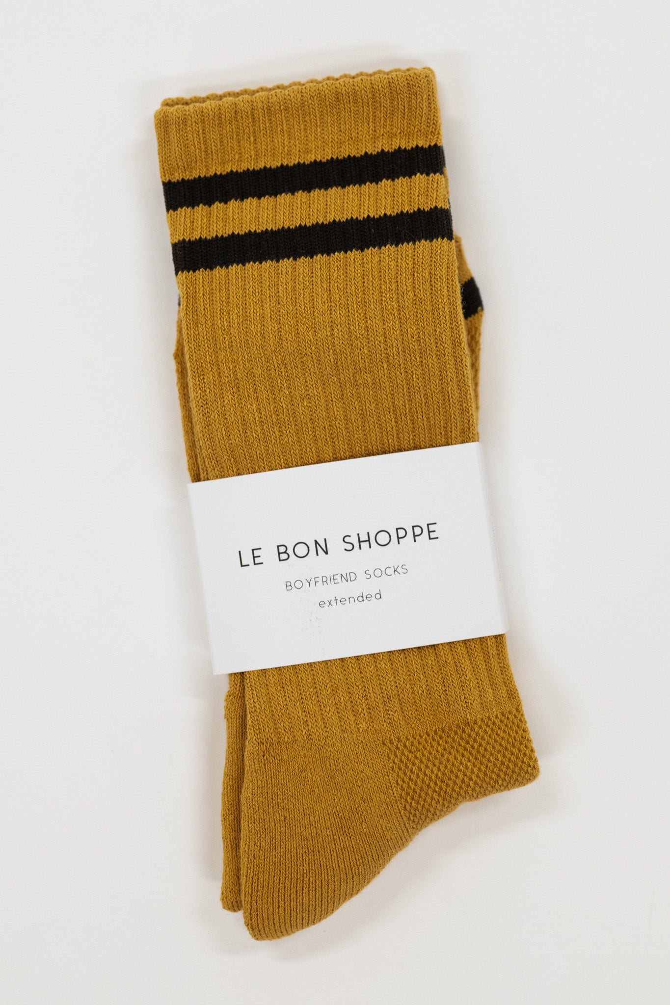 Mustard yellow socks with black stripes and a visible label on a white background