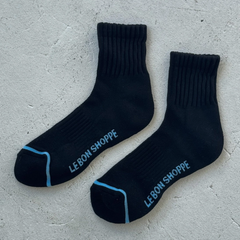 Pair of black socks with 'Le Bon Shoppe' branding on a gray surface