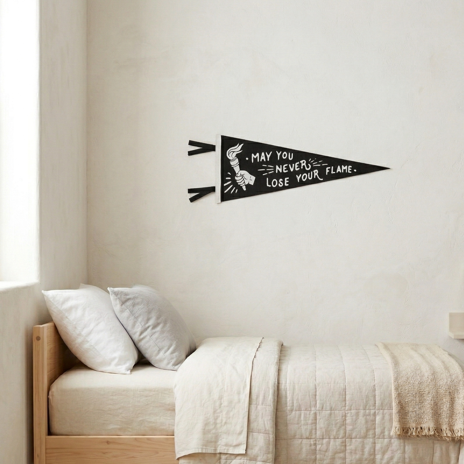 Decorative wall pennant with motivational quote above a bed in a bedroom.