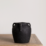 a small black vase with four handles and a chalky finish