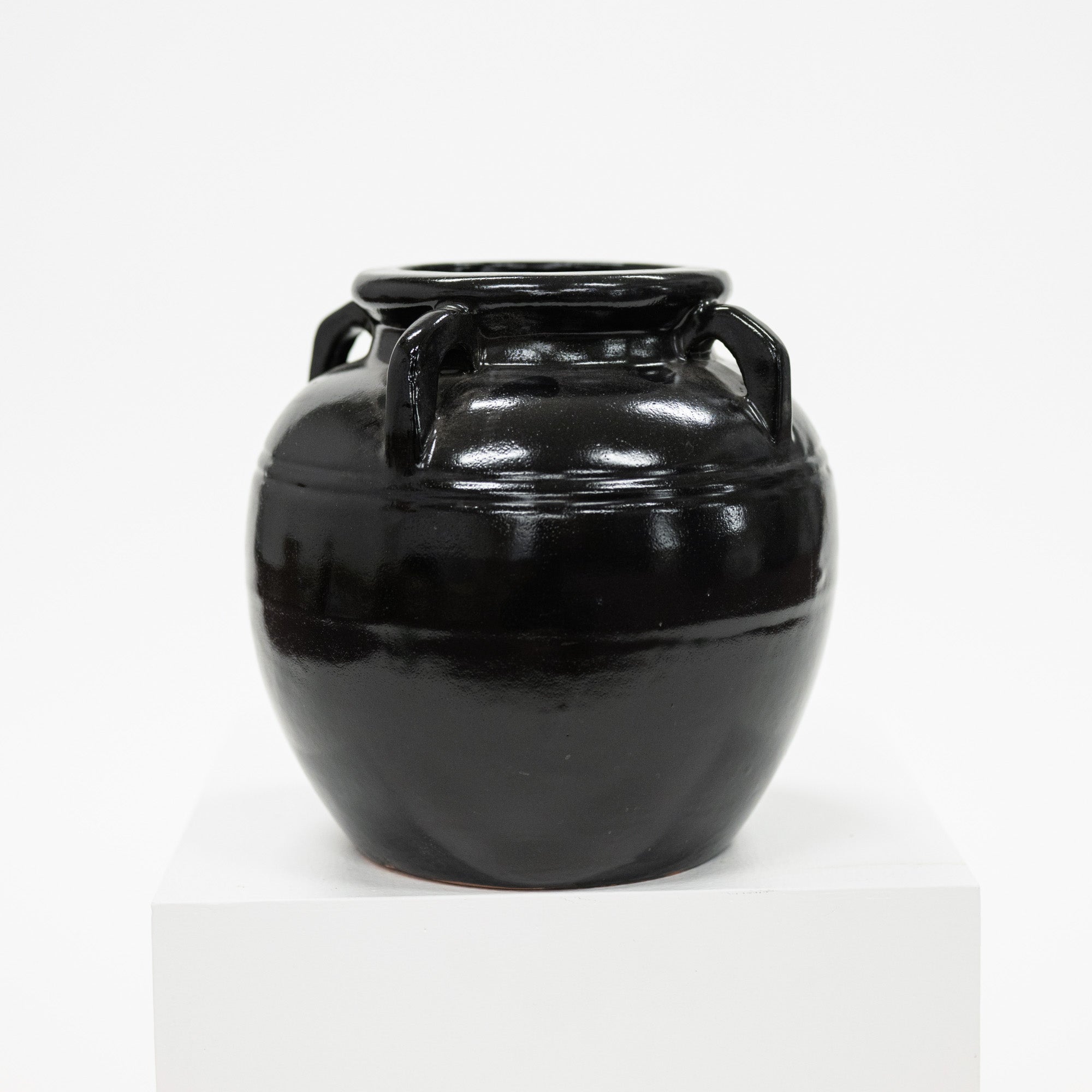Black ceramic jar with handles on a white background