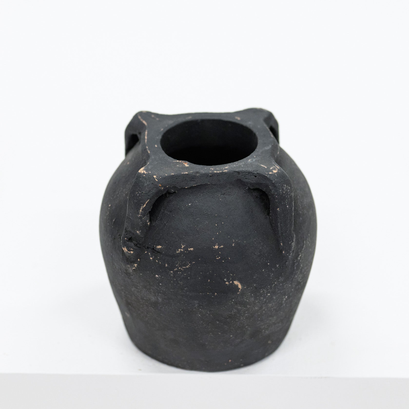 Black ceramic vase with three handles on a white background