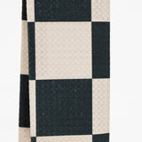 A close-up of a checkered fabric pattern with alternating black and warm off-white squares, showing a subtle woven texture.