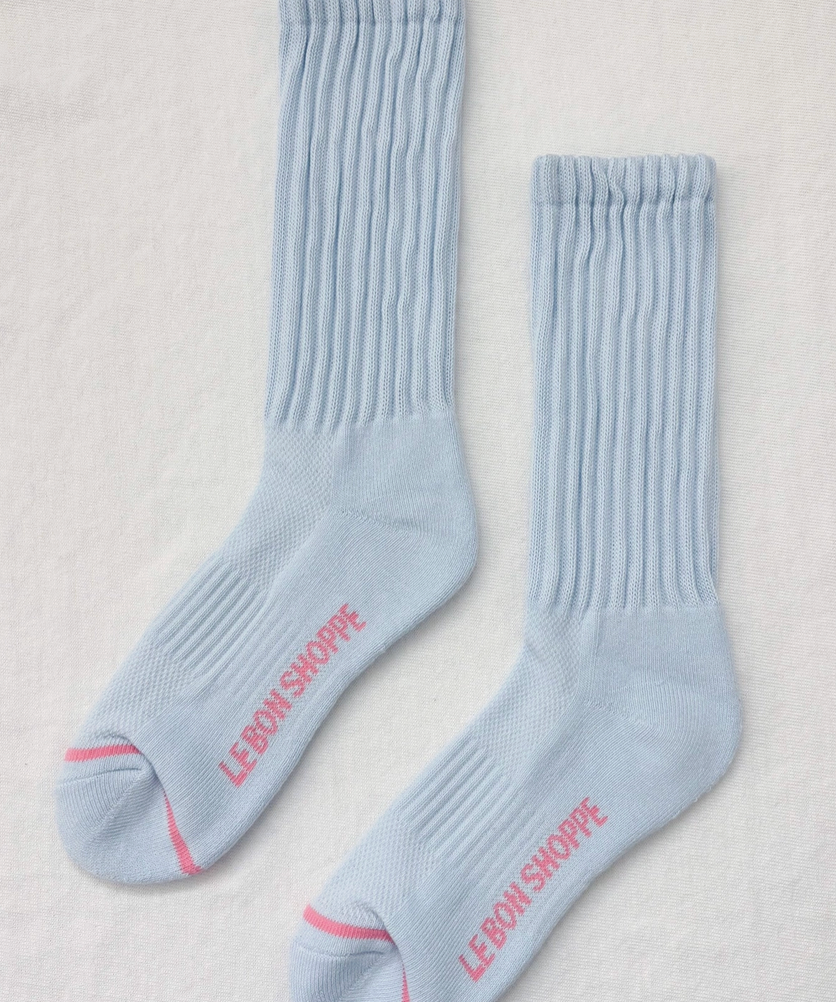 Light blue socks with pink text on a light gray background
