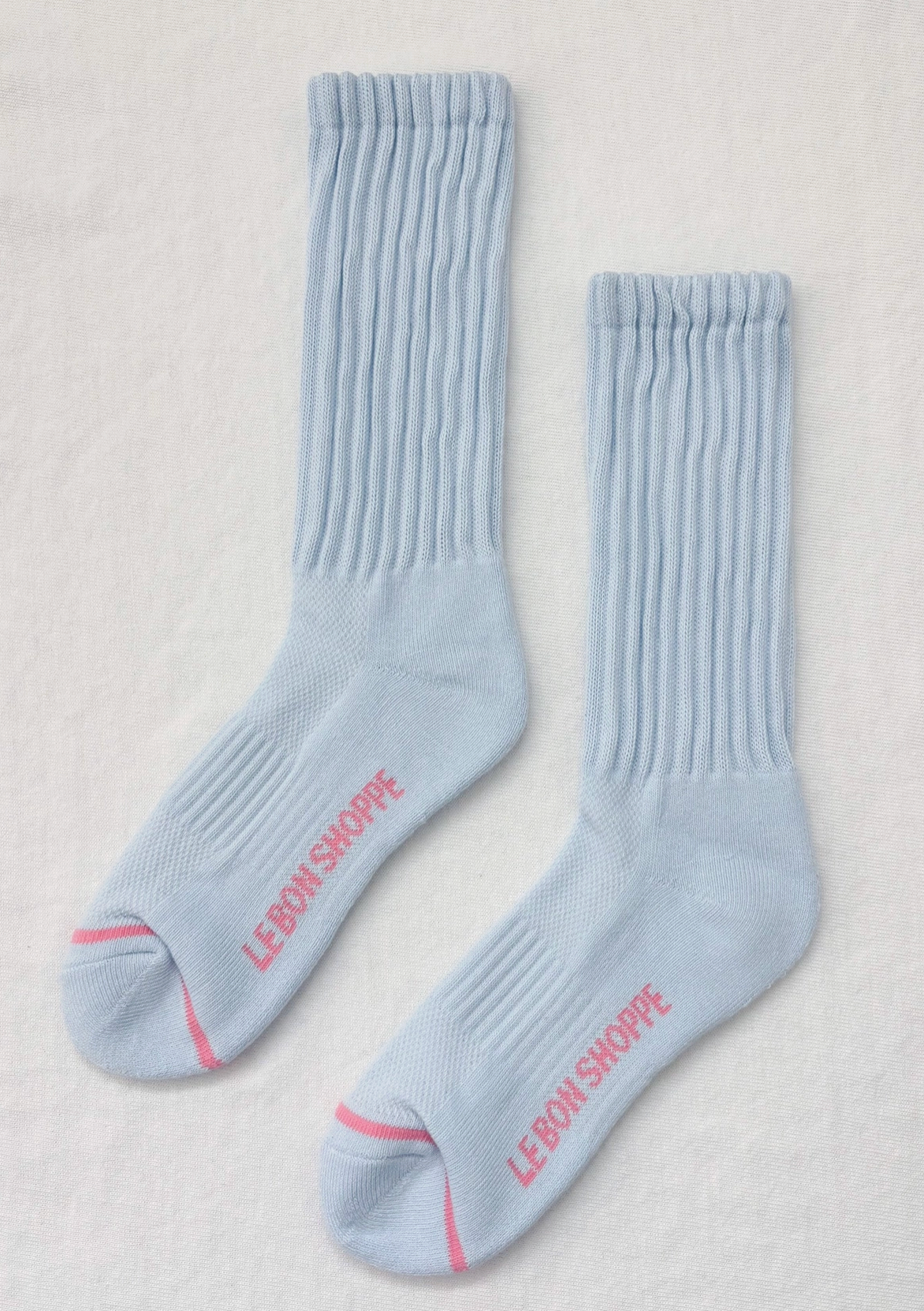 Light blue socks with pink text on a light gray background