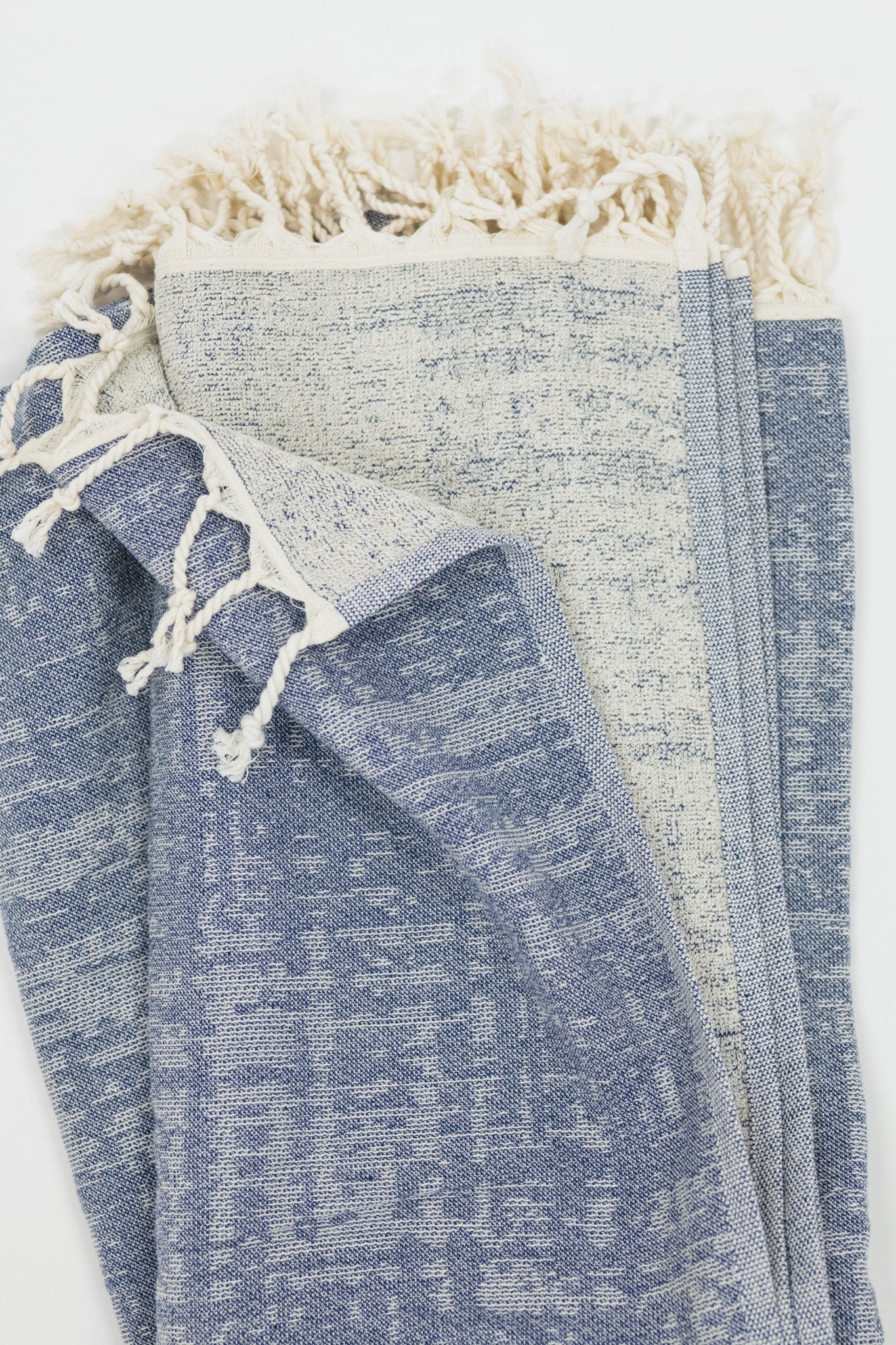 Blue crosshatch pattern beach towel with tassels on a white background