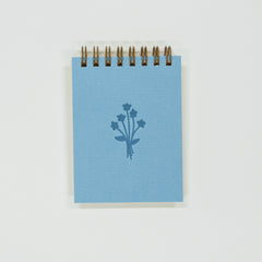 Small blue notebook with a floral design on a white background