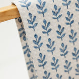 Fabric with blue leaf pattern on a wooden hanger against a white background
