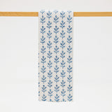 Blue floral patterned towel hanging on a wooden rod against a white background