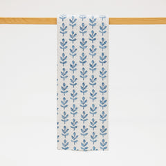 Blue floral patterned towel hanging on a wooden rod against a white background