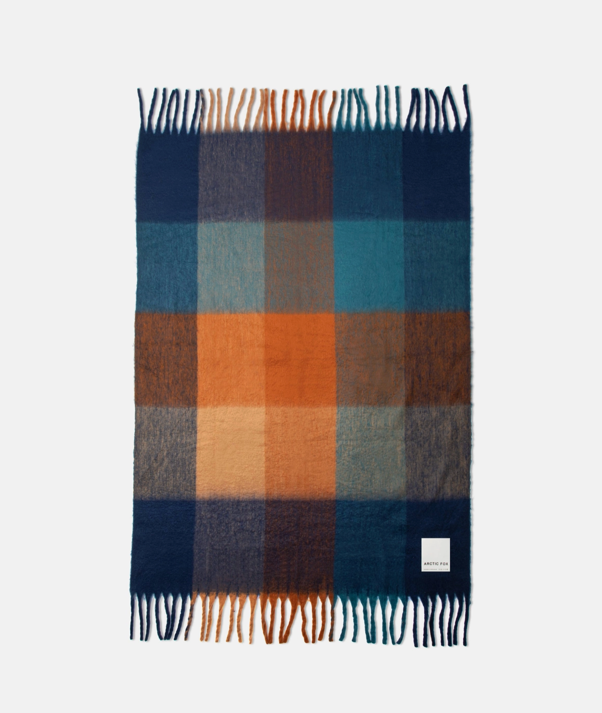 A rectangular plaid scarf with fringed ends, featuring a checkered pattern of navy blue, teal, orange, brown, and beige, displayed flat against a light gray background.