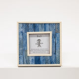 Framed artwork with blue patterned glass and white frame on a white background