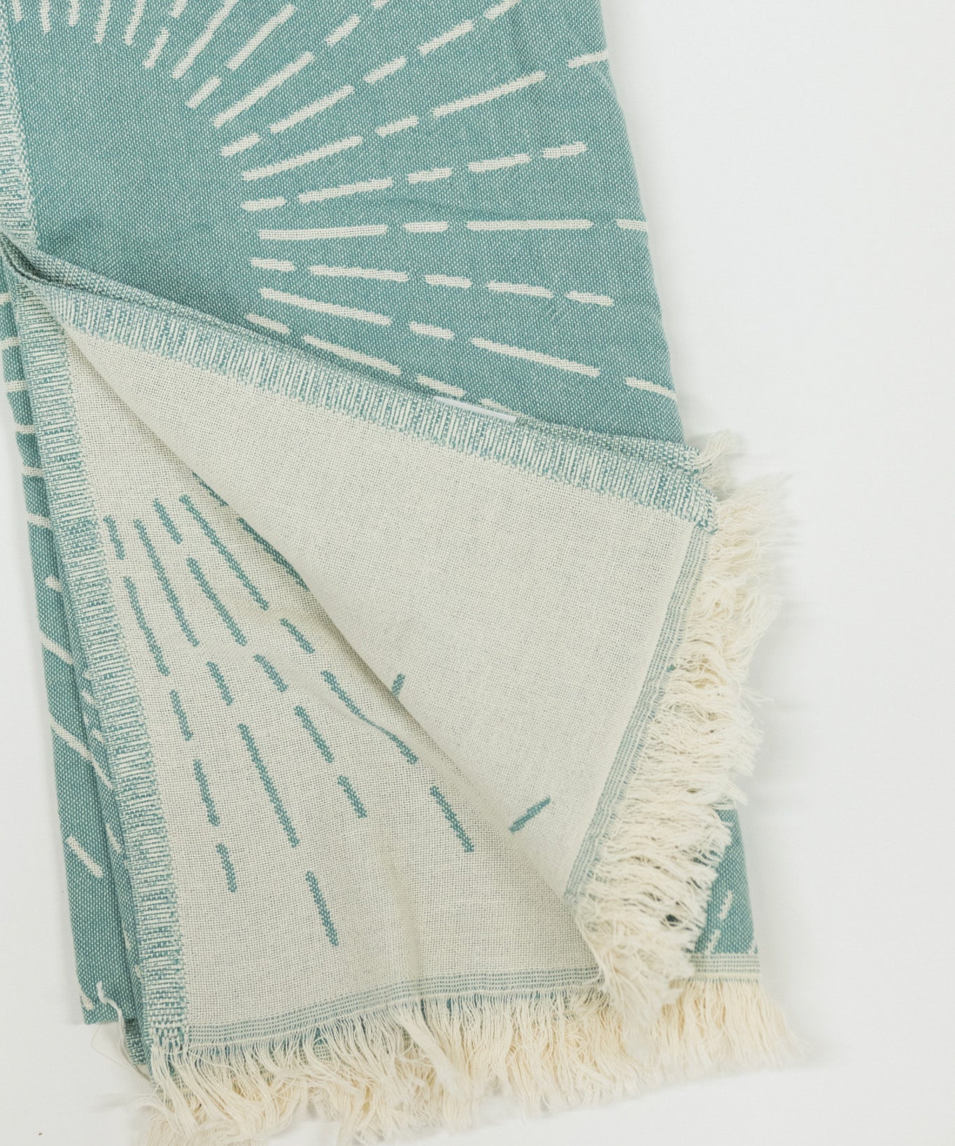 Teal and white patterned beach towel with fringes on a white background