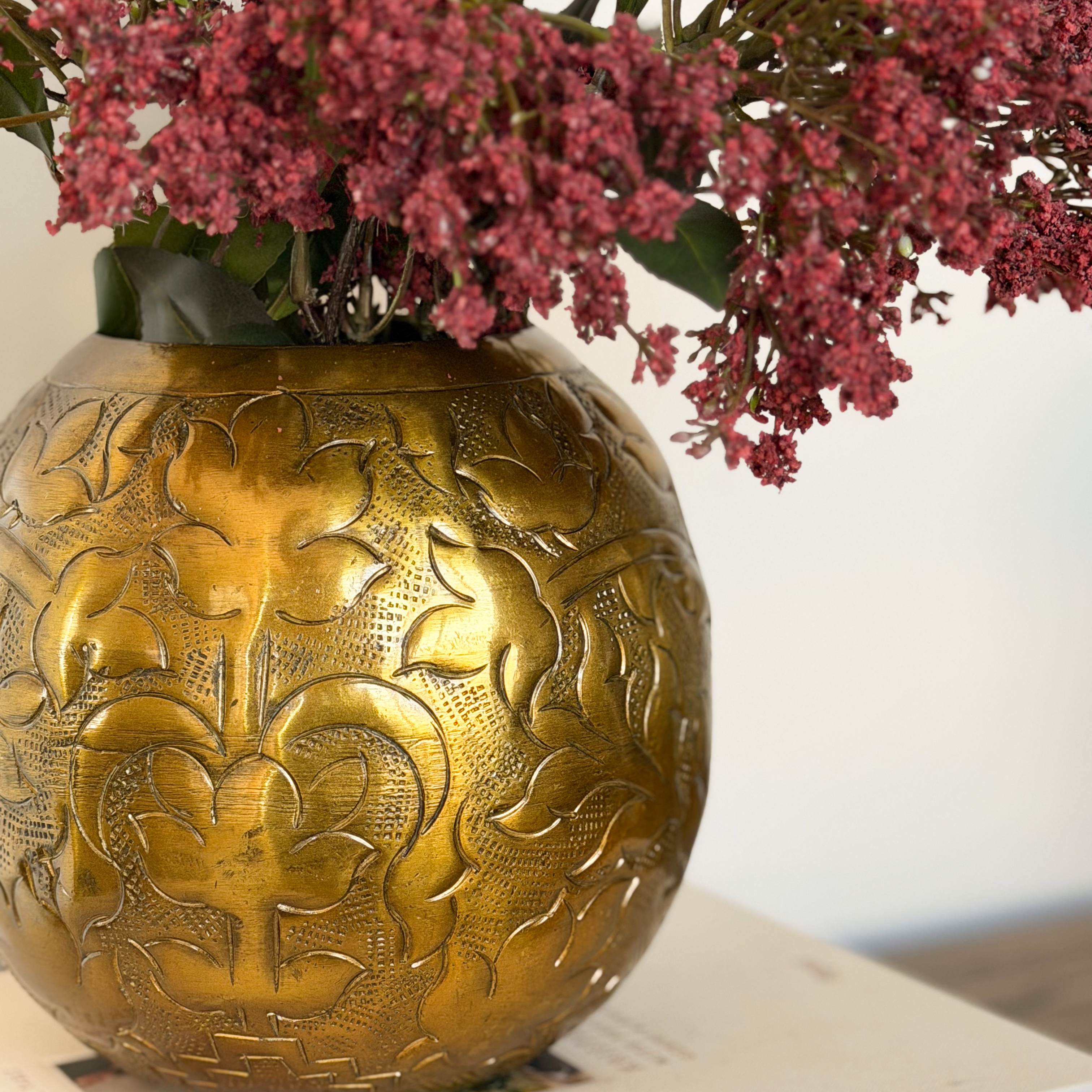 Detail shot of pressed floral pattern into a bronze metal vase.