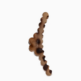 A single scalloped wavy hair claw clip in a brown and black tortoiseshell pattern, shown on a plain white background.